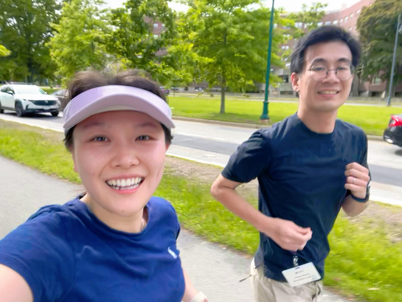 The couple taking a selfie mid-run on a tree-lined Boston path